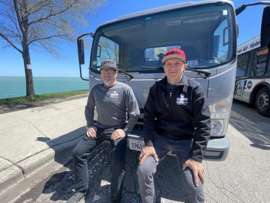Two Junk Removal Pros Sitting in Front of a 606 Junk Removal Truck
